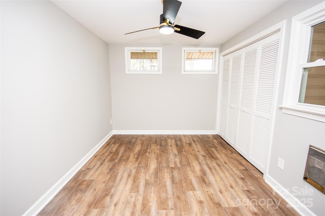 unfurnished bedroom with a closet, ceiling fan, heating unit, and light wood-type flooring