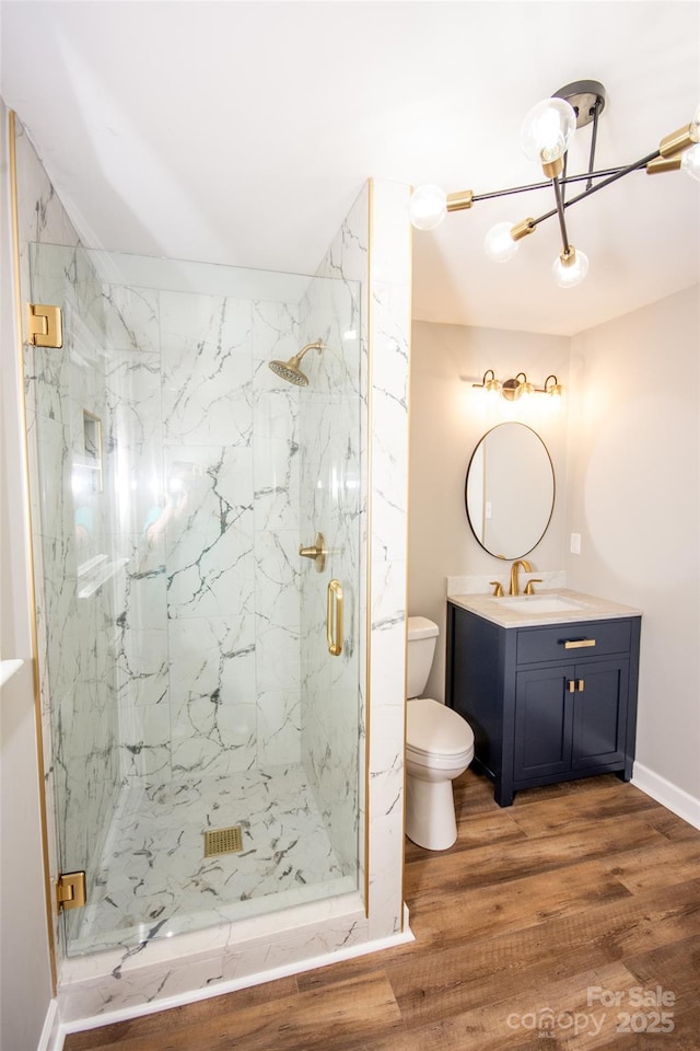 bathroom featuring wood-type flooring, an enclosed shower, vanity, and toilet