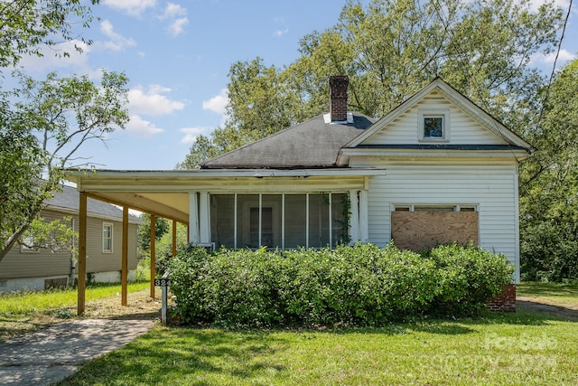 back of property featuring a sunroom and a lawn