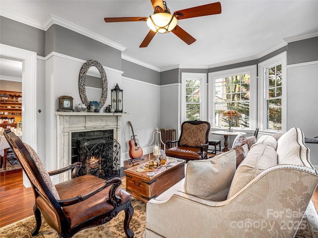 living room featuring wood-type flooring, ceiling fan, and crown molding