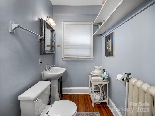 bathroom featuring toilet, radiator heating unit, and hardwood / wood-style floors