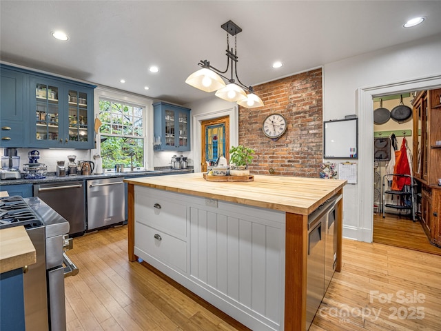 kitchen with pendant lighting, blue cabinetry, wood counters, and stainless steel appliances