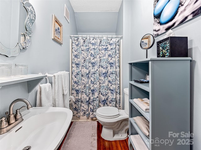 bathroom with sink, a textured ceiling, hardwood / wood-style floors, a shower with curtain, and toilet