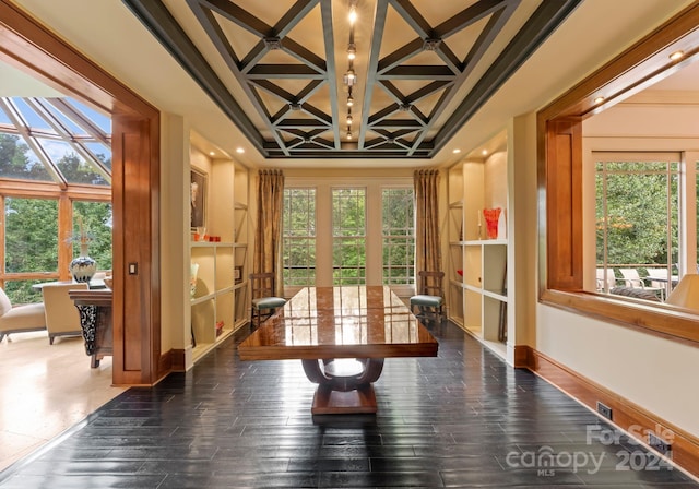 unfurnished dining area featuring coffered ceiling, plenty of natural light, dark wood-type flooring, and crown molding