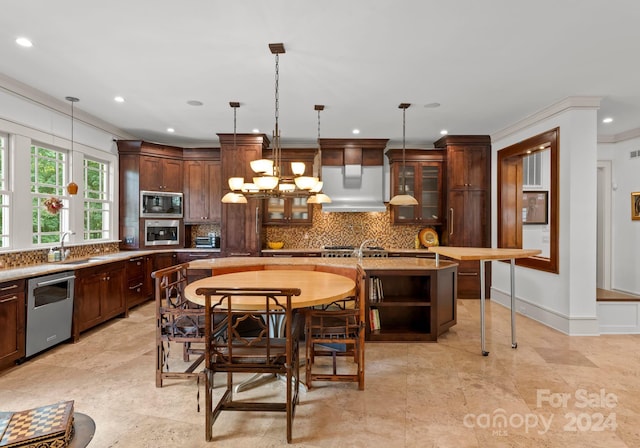 kitchen with premium range hood, hanging light fixtures, a kitchen island, stainless steel appliances, and a notable chandelier