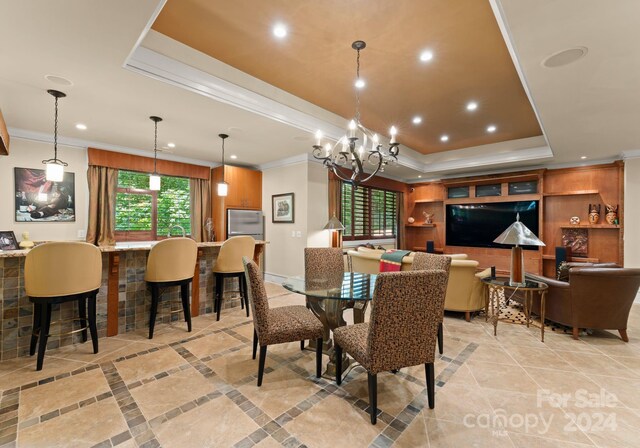 dining room with a raised ceiling, ornamental molding, and a chandelier