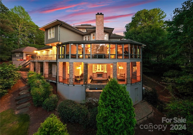 back house at dusk with a sunroom