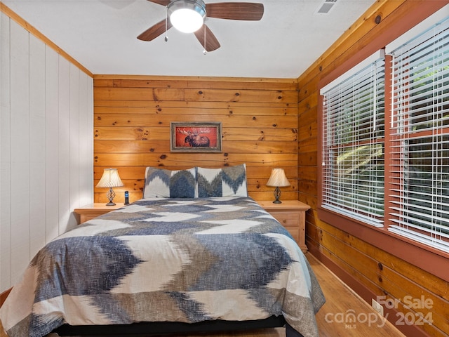 bedroom featuring ceiling fan and wooden walls