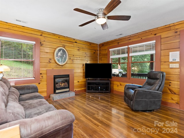 living room with wood-type flooring, ceiling fan, and wooden walls