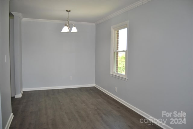 unfurnished room featuring a wealth of natural light, dark wood-type flooring, ornamental molding, and an inviting chandelier