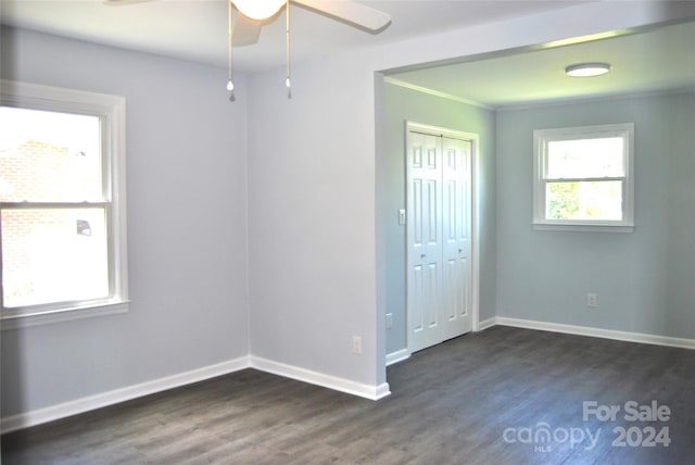 unfurnished bedroom featuring ornamental molding, dark wood-type flooring, ceiling fan, and a closet