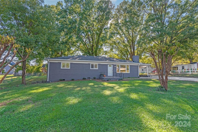 exterior space with a chimney, brick siding, fence, and a front yard