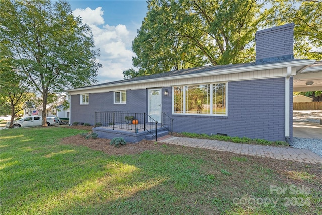 ranch-style home featuring a chimney, brick siding, and a front yard
