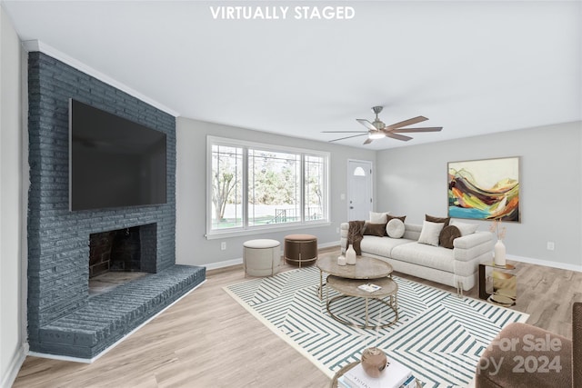 living room with ceiling fan, ornamental molding, light hardwood / wood-style flooring, and a brick fireplace