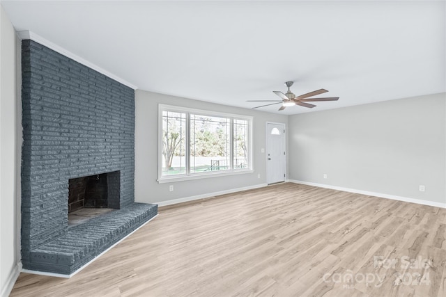 unfurnished living room with light wood finished floors, a brick fireplace, baseboards, and ceiling fan