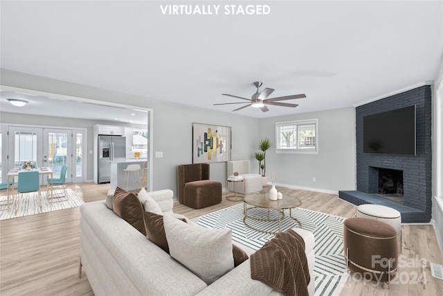 living area featuring light wood-style flooring, visible vents, baseboards, a ceiling fan, and a fireplace