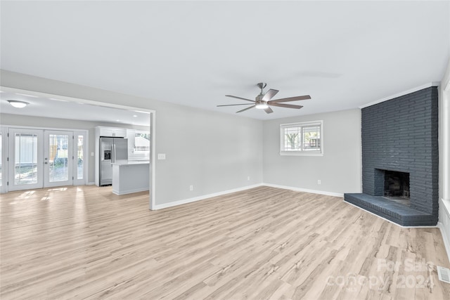 unfurnished living room with french doors, light hardwood / wood-style floors, a brick fireplace, and ceiling fan