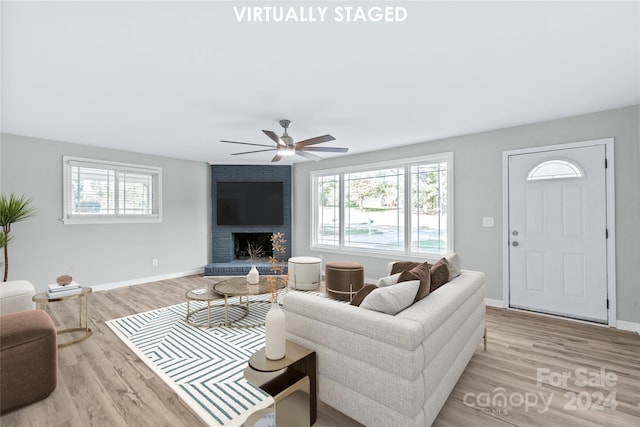 living room with light hardwood / wood-style floors, a fireplace, and ceiling fan