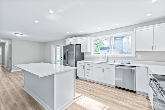 kitchen with a center island, white cabinets, stainless steel appliances, and light wood-type flooring