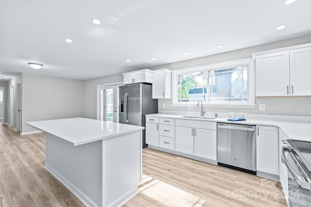 kitchen with white cabinetry, a center island, stainless steel appliances, and a sink