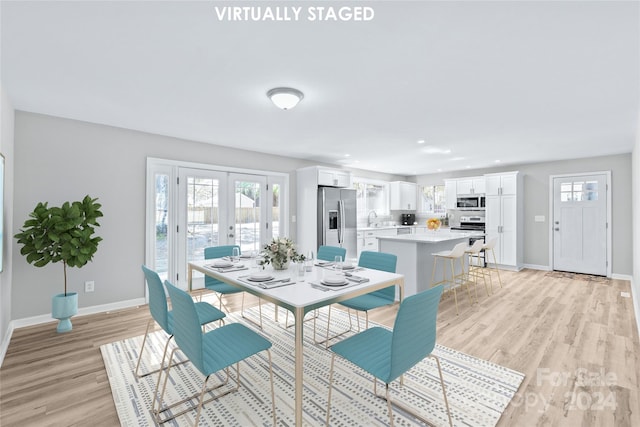 dining space featuring french doors, sink, and light wood-type flooring