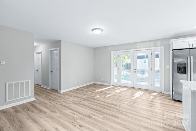 unfurnished living room with baseboards, french doors, visible vents, and light wood-style flooring