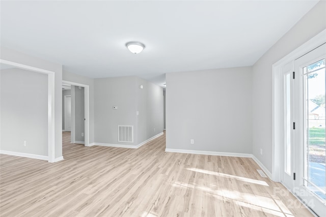 spare room with light wood-type flooring, baseboards, and visible vents