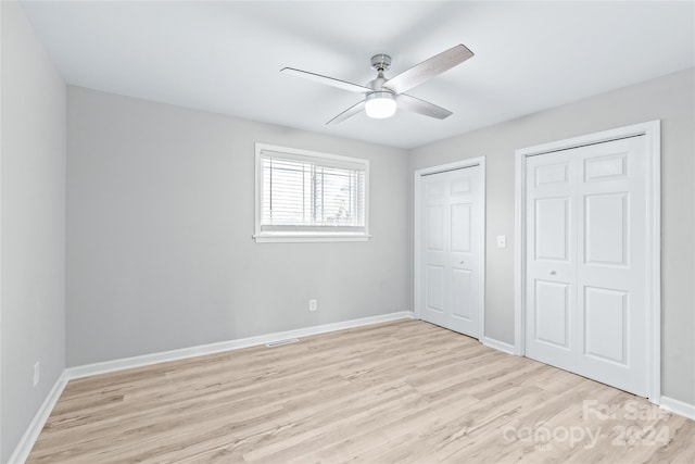 unfurnished bedroom featuring light hardwood / wood-style floors, two closets, and ceiling fan