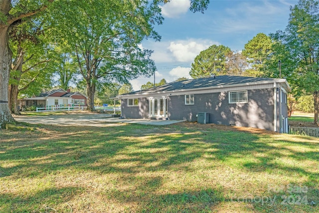 rear view of house with a patio, central AC, and a lawn