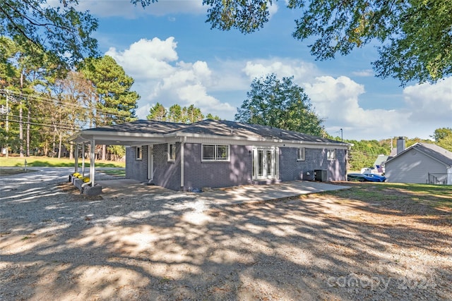 rear view of house with brick siding, a patio, driveway, and an attached carport