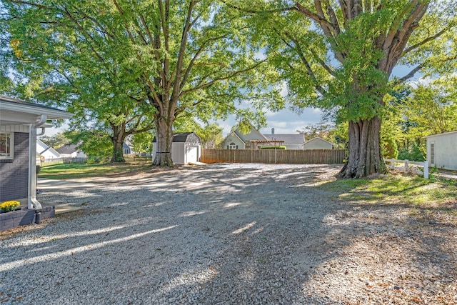 view of yard with fence, an outbuilding, and a storage shed