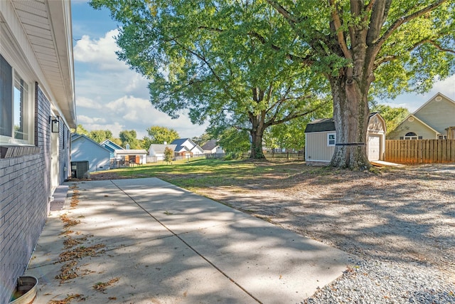 view of patio featuring an outdoor structure, a residential view, a shed, and fence