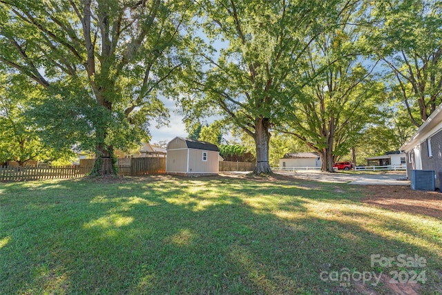 view of yard featuring fence, an outbuilding, cooling unit, and a shed