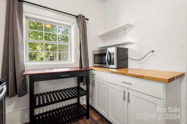 kitchen featuring dark wood-type flooring, butcher block counters, and white cabinetry