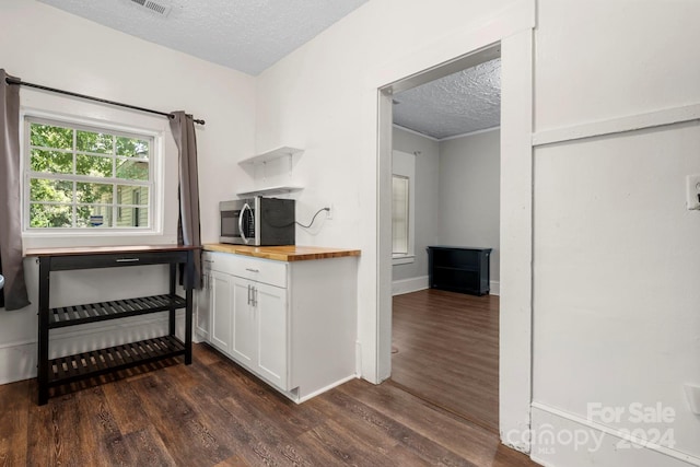 kitchen with a textured ceiling, butcher block counters, dark hardwood / wood-style flooring, and white cabinets