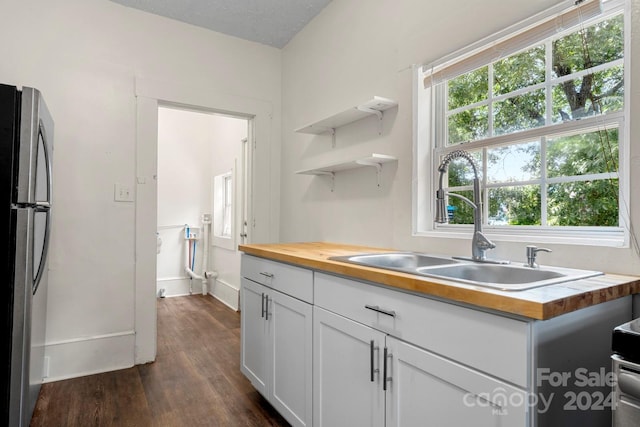 kitchen featuring white cabinetry, sink, butcher block countertops, stainless steel fridge, and dark hardwood / wood-style floors