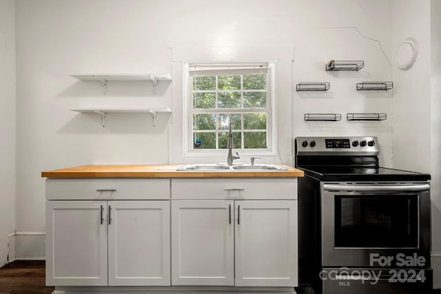 225 Flint St, Charlotte, NC 28216 - kitchen with stainless steel electric range, white cabinetry, open shelves, wooden counters, and a sink