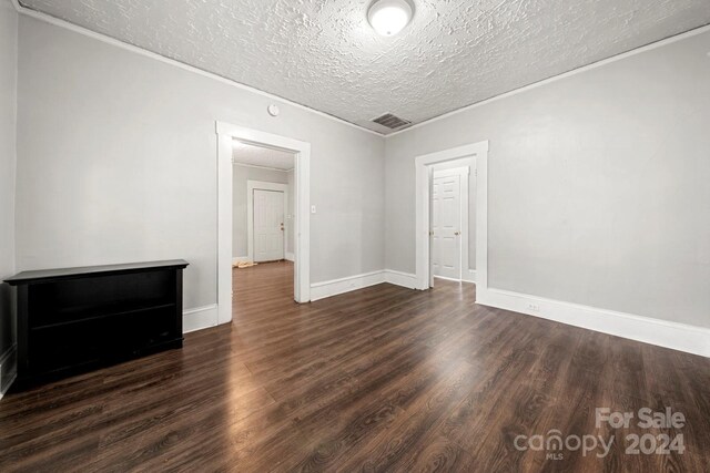 empty room with dark wood-type flooring and a textured ceiling