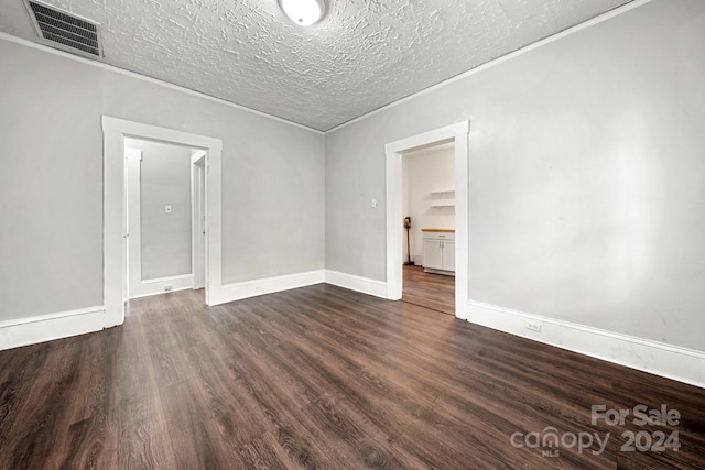 empty room featuring a textured ceiling and dark hardwood / wood-style floors