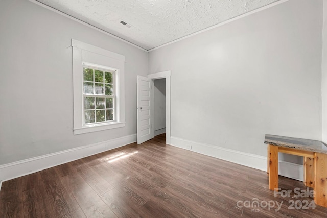 empty room with dark hardwood / wood-style flooring and a textured ceiling