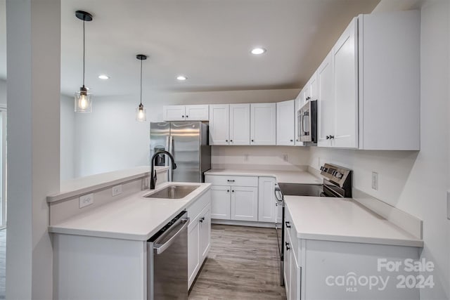 kitchen with light wood-type flooring, sink, white cabinets, stainless steel appliances, and decorative light fixtures