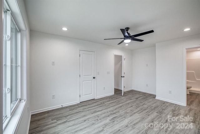 unfurnished bedroom featuring light wood-type flooring, ensuite bath, and ceiling fan