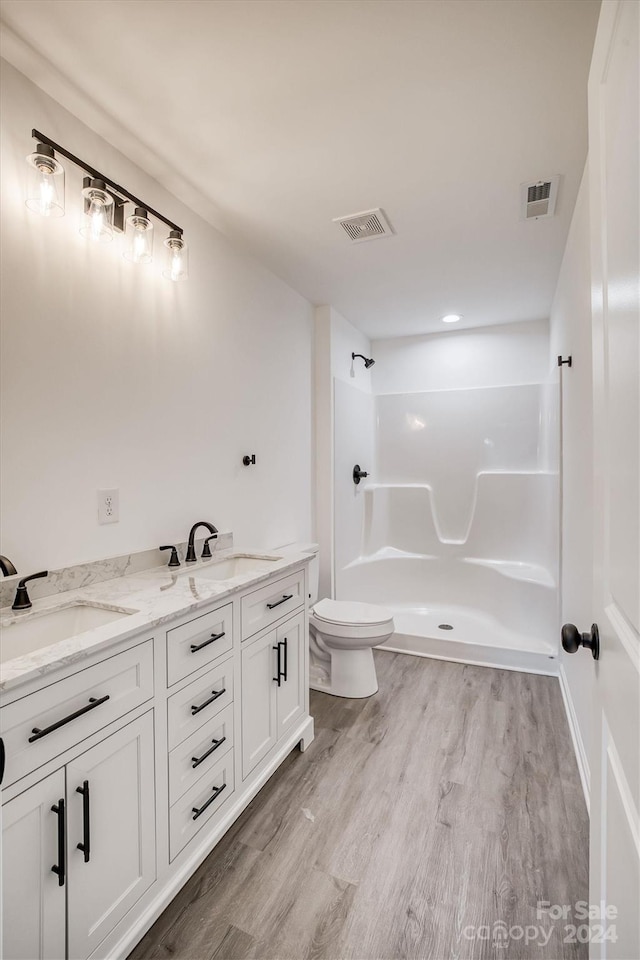 bathroom with a shower, hardwood / wood-style floors, toilet, and vanity