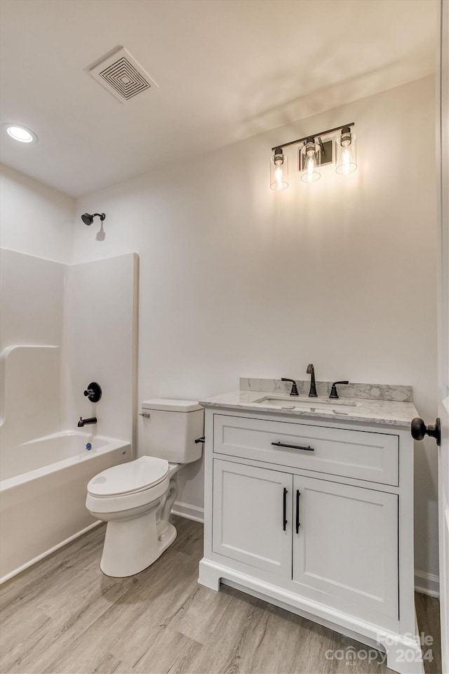 full bathroom featuring hardwood / wood-style flooring, bathing tub / shower combination, vanity, and toilet