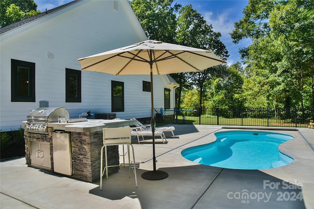 view of pool featuring area for grilling, an outdoor kitchen, and a patio area