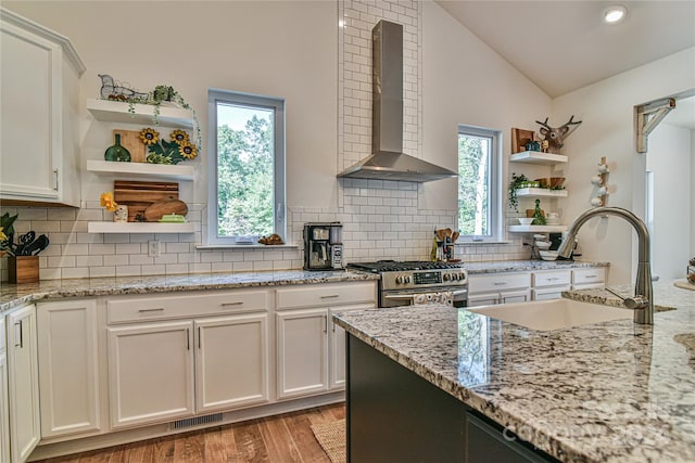 kitchen with light hardwood / wood-style flooring, vaulted ceiling, sink, wall chimney exhaust hood, and high end stove