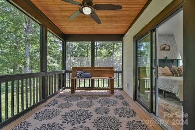 unfurnished sunroom featuring ceiling fan, plenty of natural light, and wooden ceiling