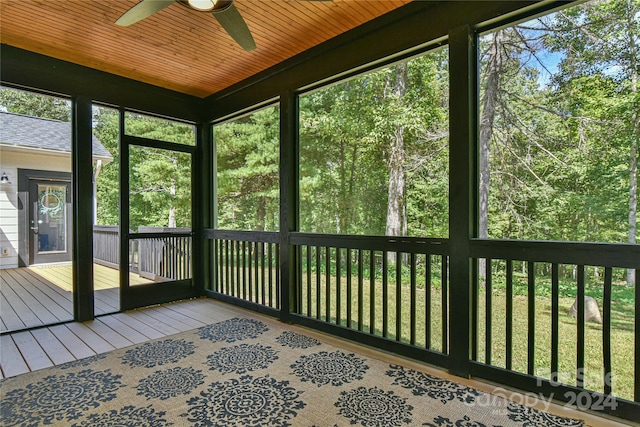 unfurnished sunroom with a healthy amount of sunlight, ceiling fan, and wooden ceiling