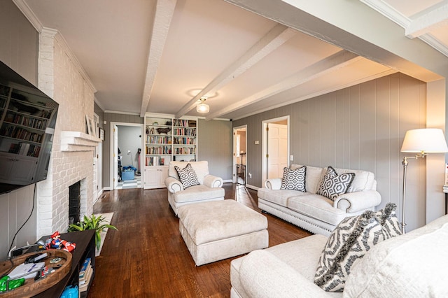 living room with dark wood-type flooring, crown molding, beamed ceiling, and a fireplace