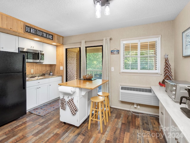 kitchen featuring appliances with stainless steel finishes, dark hardwood / wood-style flooring, white cabinetry, and a breakfast bar